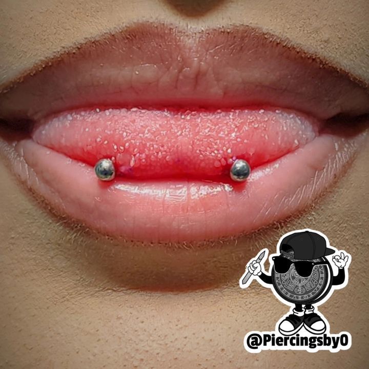 a woman's tongue with two piercings on the top and bottom of it