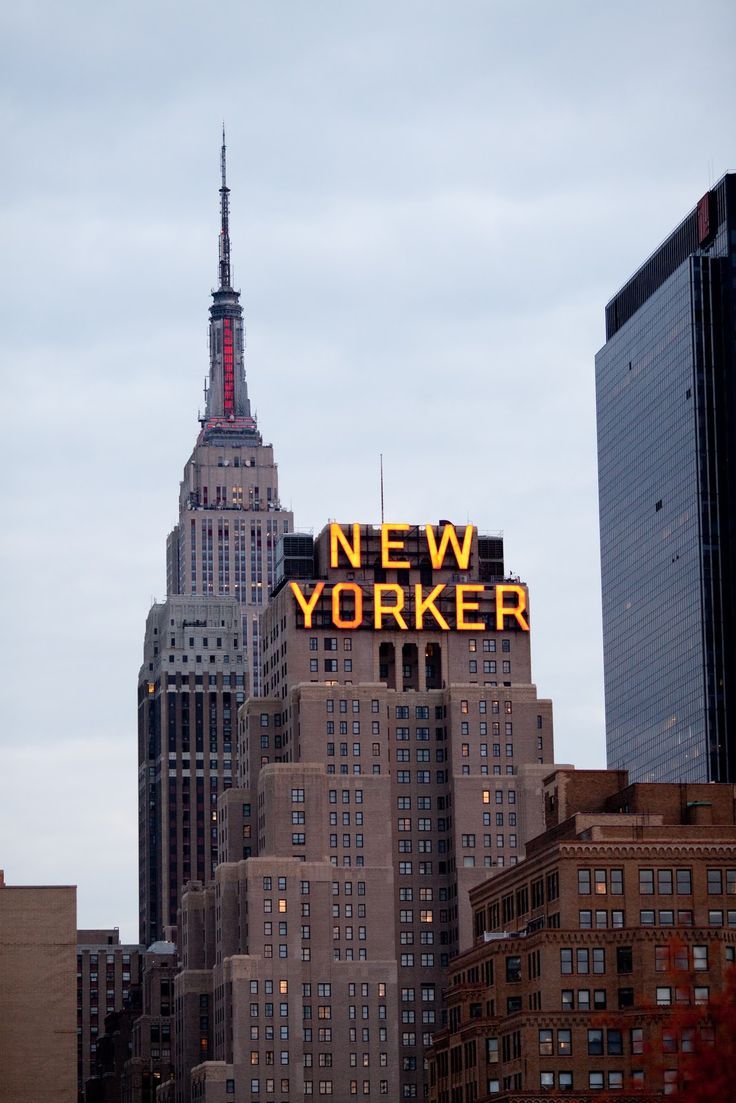 the new york sign is lit up in front of some tall buildings and skyscrapers