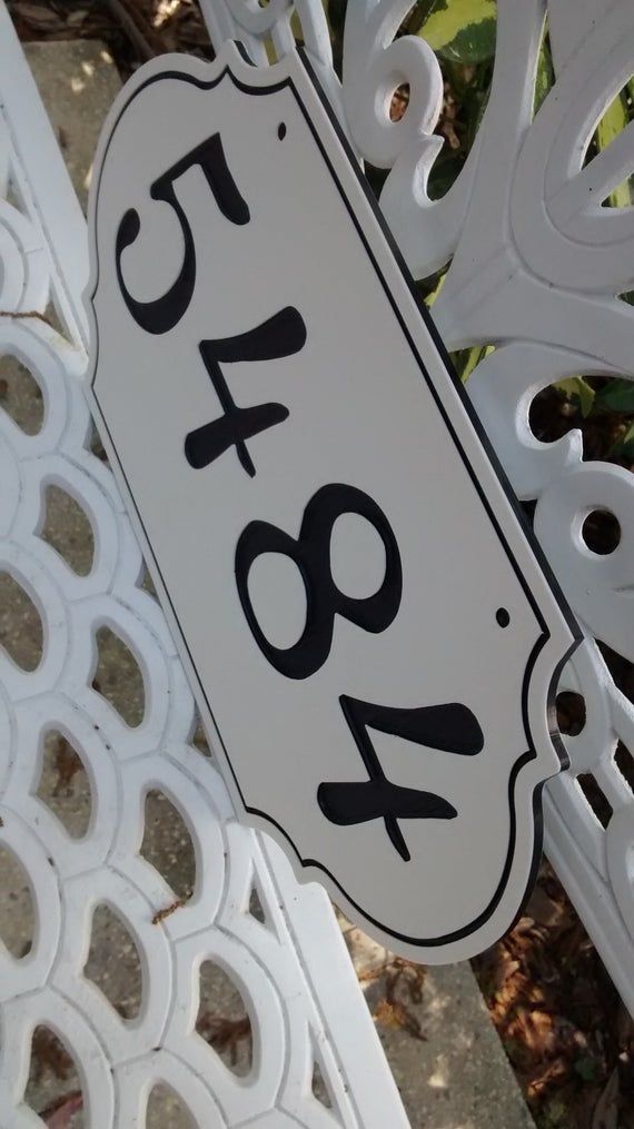 a close up of a white sign with black numbers on it's sides and an iron fence in the background