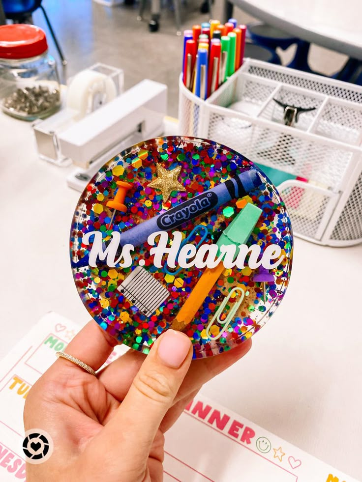 a person holding up a sticker that says ms heaner surrounded by confetti and scissors