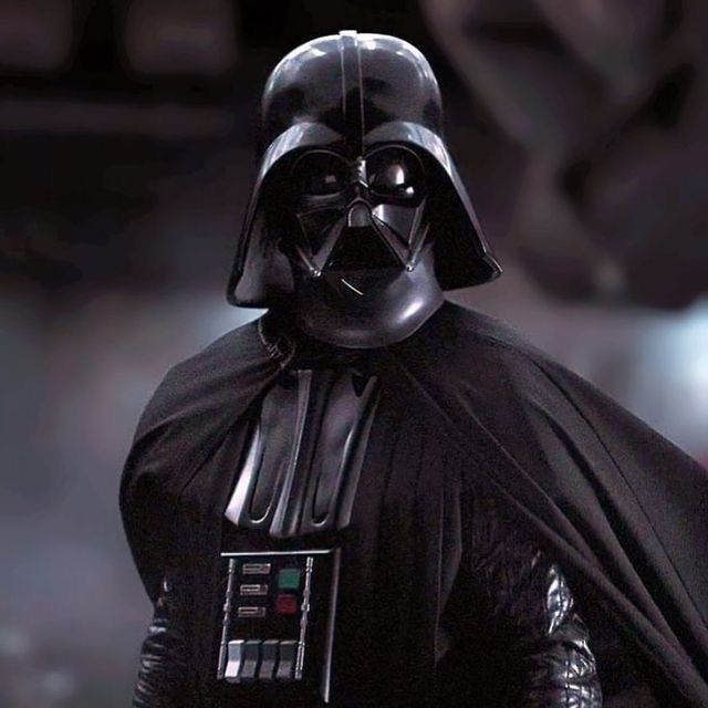 darth vader is standing in the dark