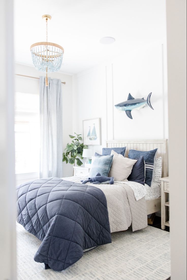 a bed room with a neatly made bed and a chandelier hanging from the ceiling