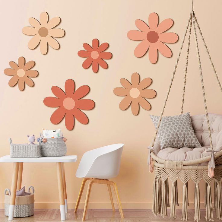 a baby's room with pink and orange flowers on the wall, hanging from a rope