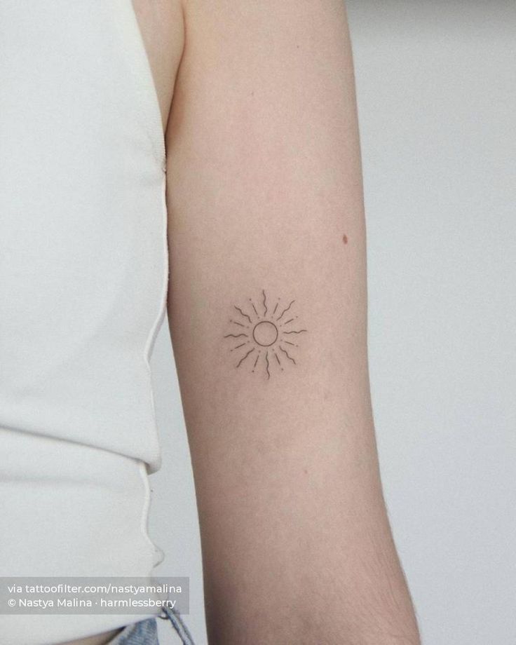 a woman's arm with a small sun tattoo on the back of her left arm