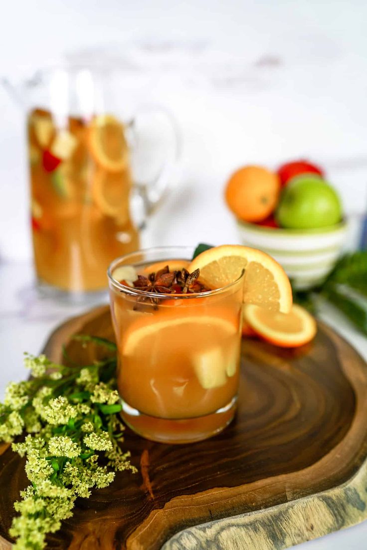 two glasses filled with drinks sitting on top of a wooden tray next to some fruit