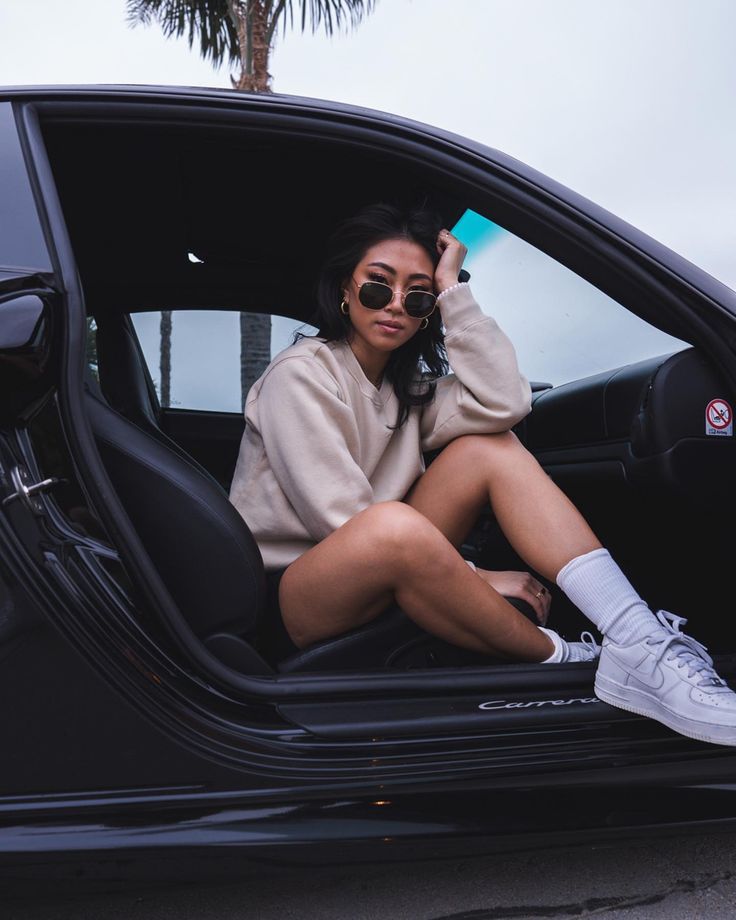 a woman sitting in the drivers seat of a car with her feet on the door