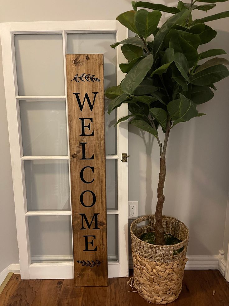 a wooden welcome sign next to a potted plant