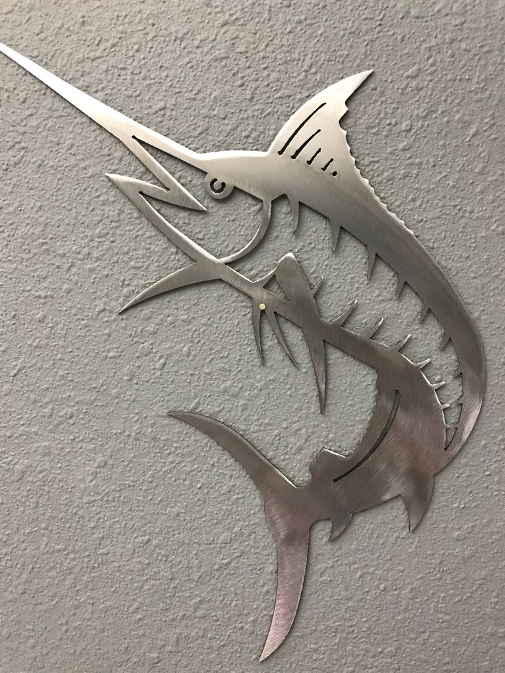 a metal fish wall hanging on the side of a building