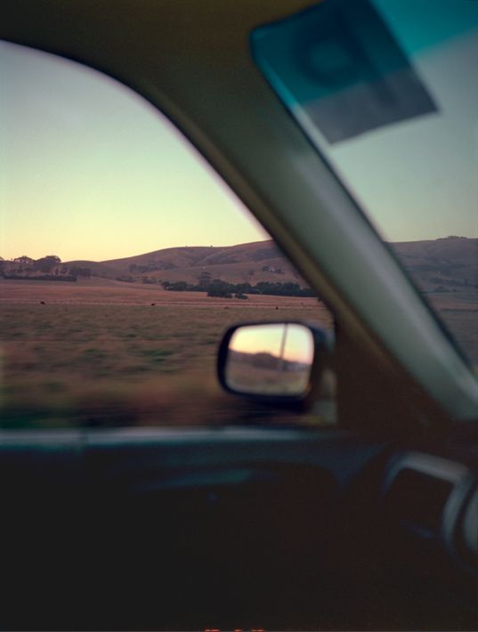 the view from inside a car looking out at an open field and mountains in the distance