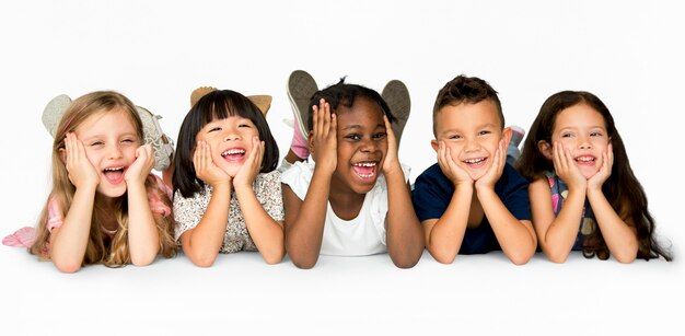 four children are laying on the floor with their hands in front of their faces and smiling