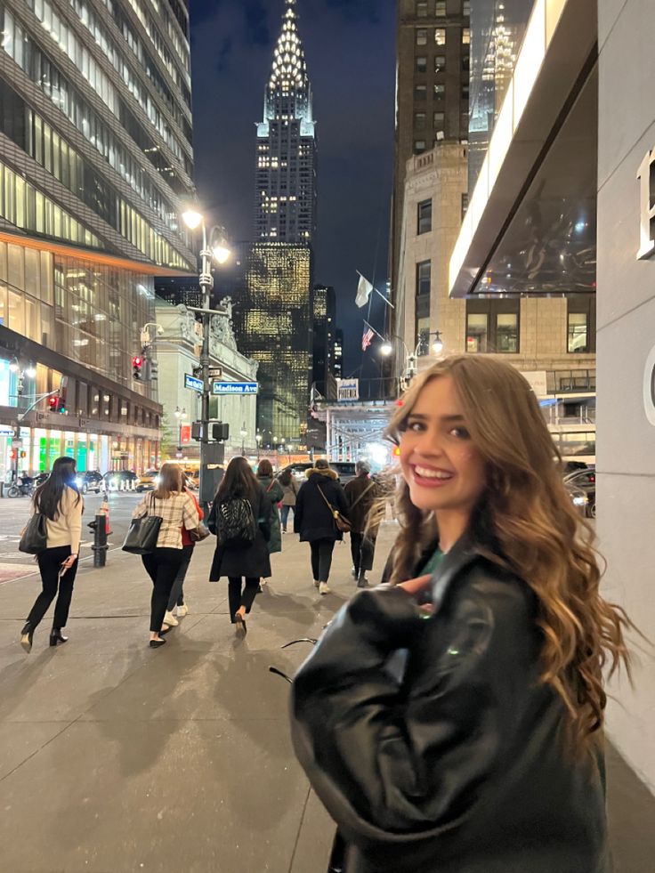 a woman standing in the middle of a city at night