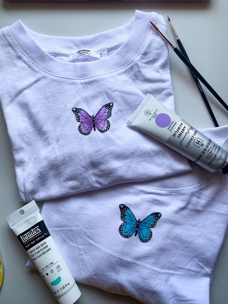 Hand painted butterflies on t shirts Tee Shirt Painting Diy, Fabric Painting On Tshirts Design, Ideas For Tshirt Painting, White Shirt Diy Paint, Painting Shirts Aesthetic, Fabric Painting Aesthetic, Hand Painted Butterfly On Fabric, Painting On Tshirts Aesthetic, Tshirts Painting Ideas