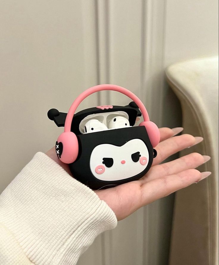 a hand holding a black and white case with pink headphones on it's face