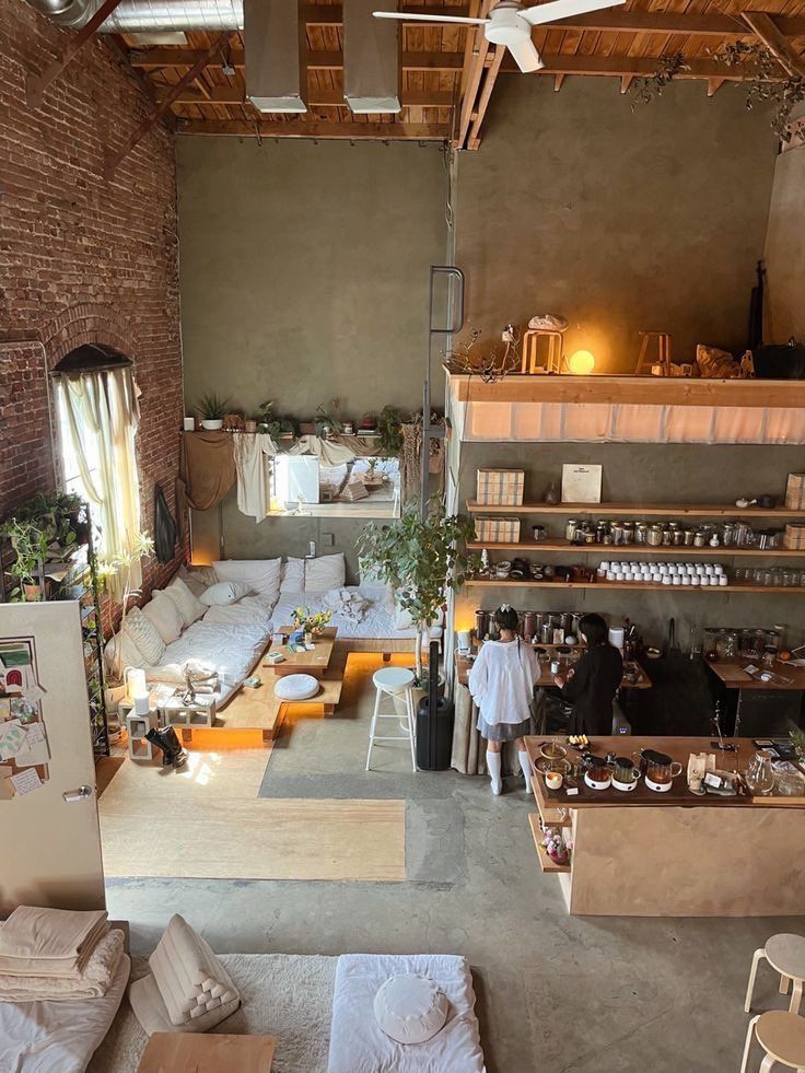 an overhead view of a living room and dining area with exposed brick walls, concrete flooring and open shelving