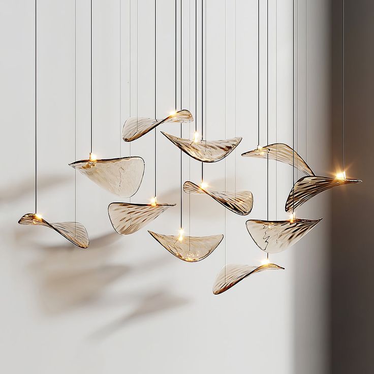 a group of lights hanging from strings in the shape of boats on a wall next to a window