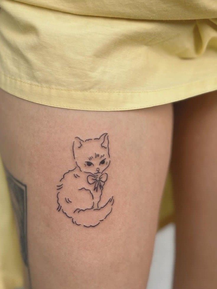 a small cat tattoo on the thigh