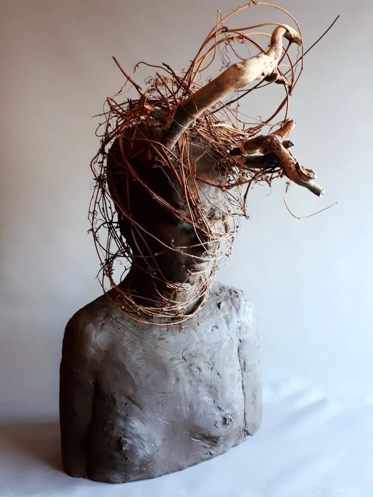 a bird is perched on top of a rock with branches in it's beak