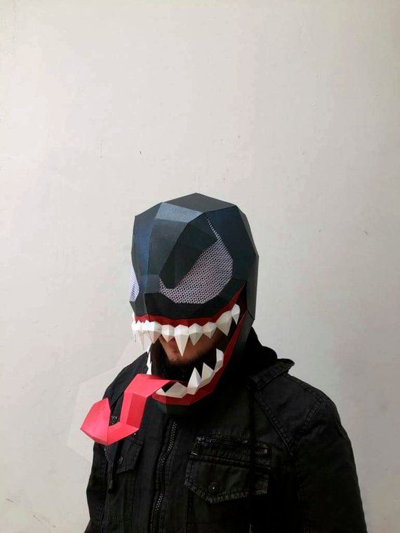 a man wearing a mask with teeth and fangs on it's face, standing in front of a white wall