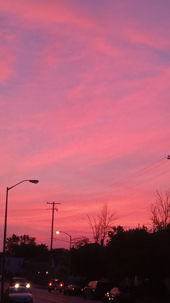 cars are parked on the side of the road as the sun sets in the distance