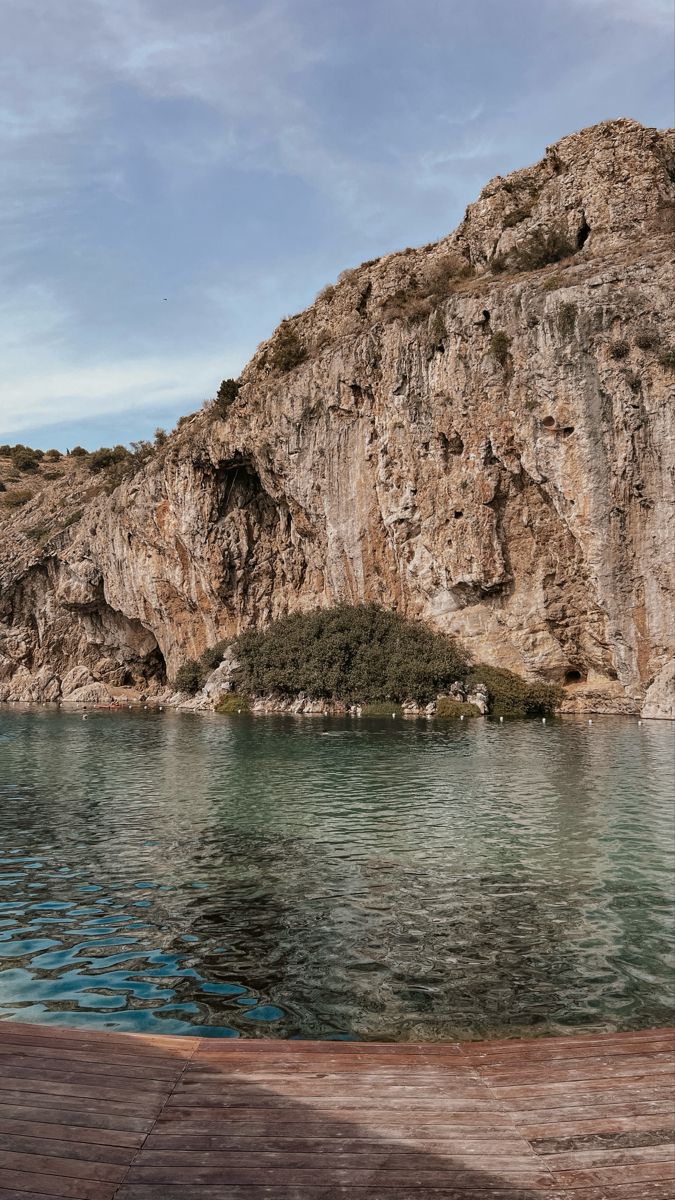 a body of water next to a rocky cliff