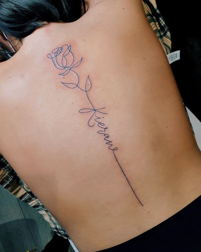 a woman's back with a rose tattoo on her left side and the word love written in cursive writing