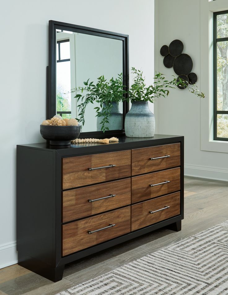 a dresser with a mirror and vase on top