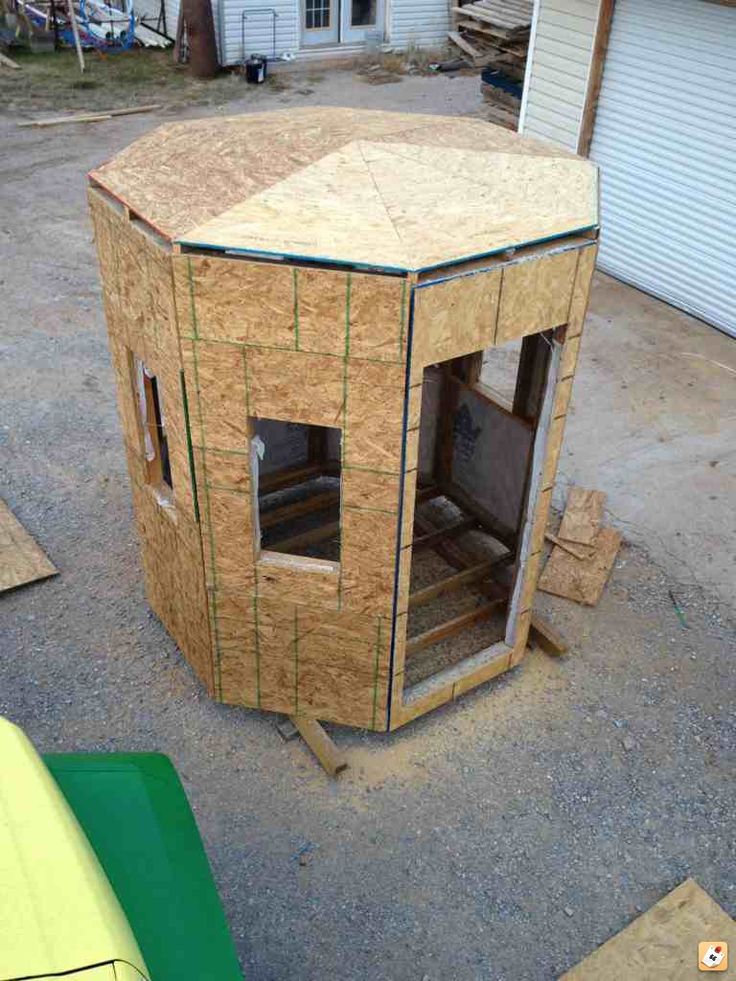 a small wooden structure sitting in the middle of a yard next to a building that is being built