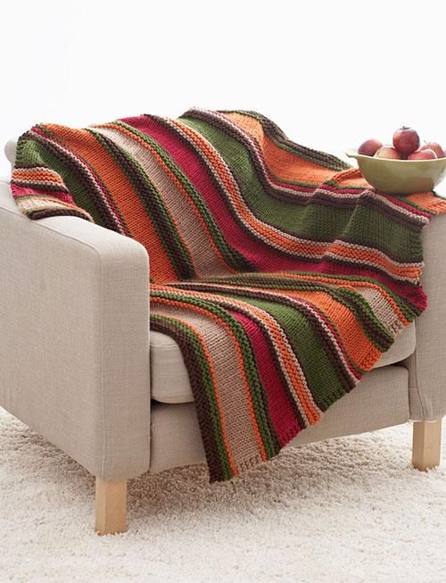 a chair with a blanket on top of it in front of a bowl of fruit