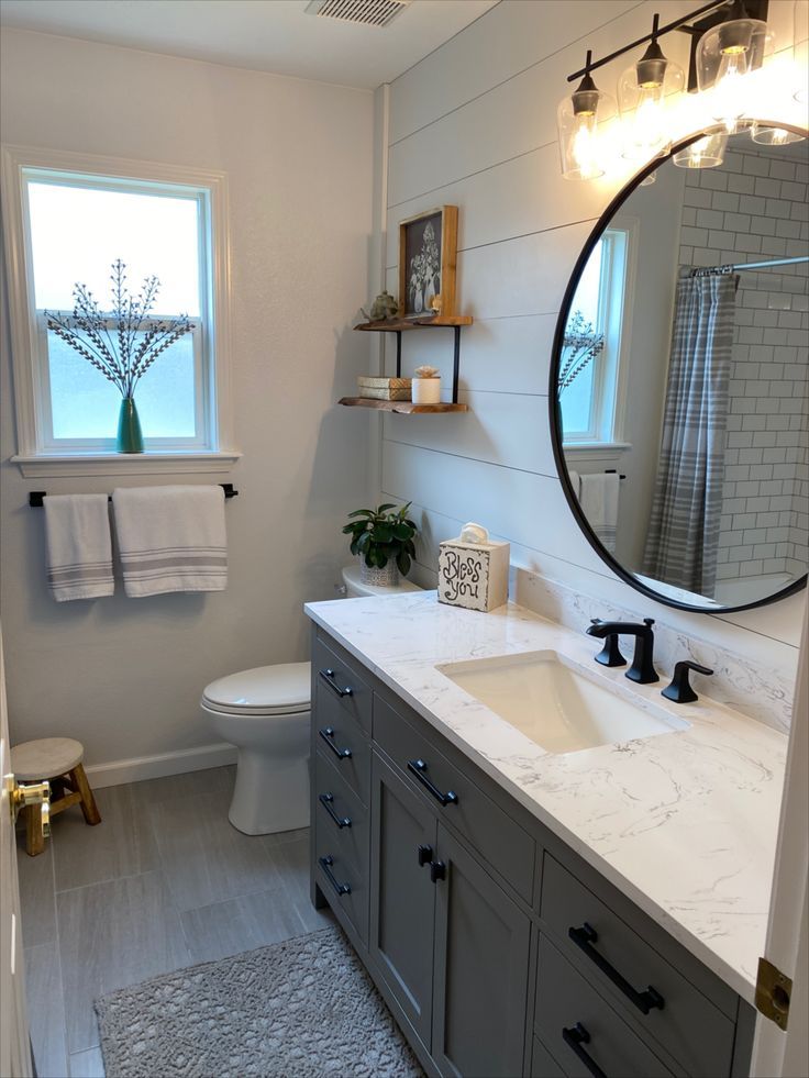 a bathroom with a sink, mirror and toilet in it's corner next to a window