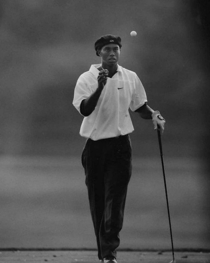 black and white photograph of a man holding a golf club with a ball in the air