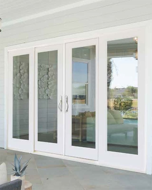 an outside patio area with white doors and glass windows on the side of the house