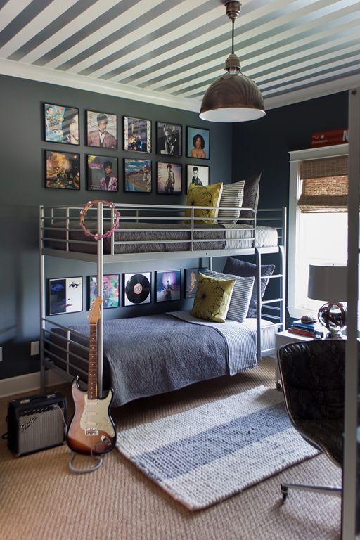 a bedroom with a bunk bed, guitar and pictures on the wall