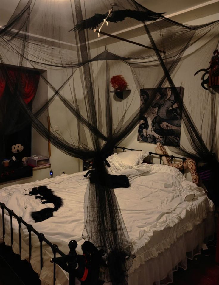 a bed with black netting on it and decorations hanging from the headboard, in a bedroom decorated for halloween