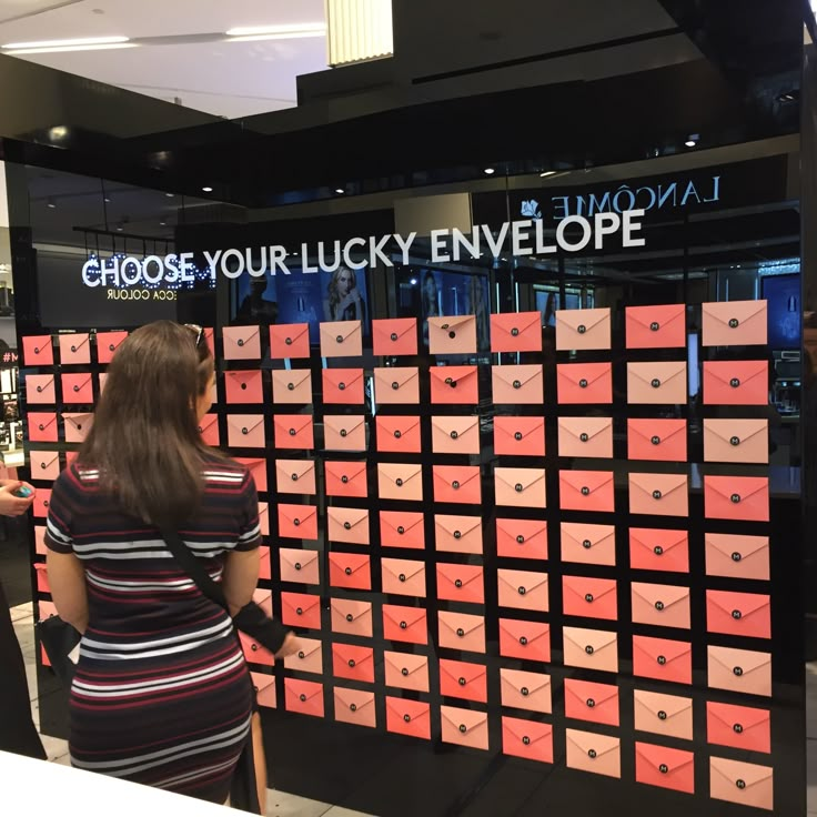 a woman standing in front of a display with lots of pink and orange boxes on it