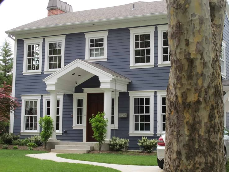 a blue house with white trim on the front door and windows is seen in this image