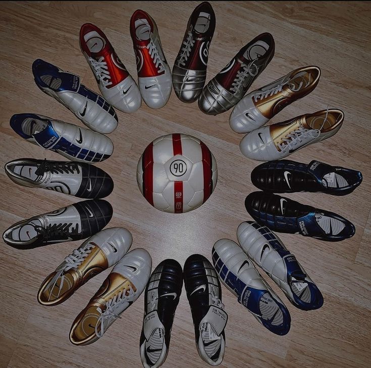 a group of shoes sitting in the middle of a soccer ball on top of a wooden floor