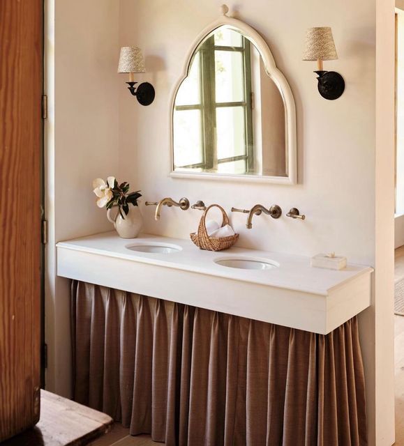 a bathroom with two sinks and a mirror on the wall above it, along with an arched window