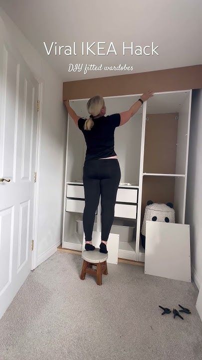 a woman standing on top of a step stool in front of an open closet door