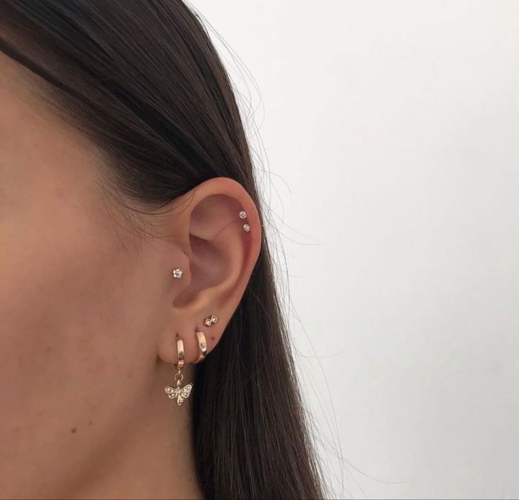 a close up of a person's ear wearing gold and silver earrings with stars on them