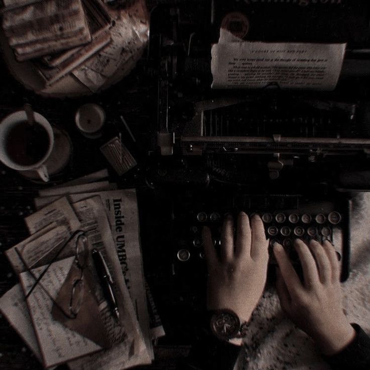 a person typing on an old typewriter surrounded by papers and other things that are scattered around