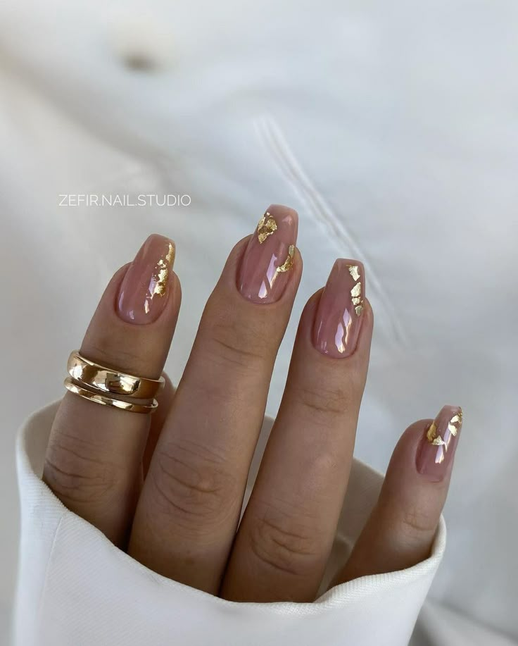 a woman's hand with two gold rings on her fingers and some pink nail polish