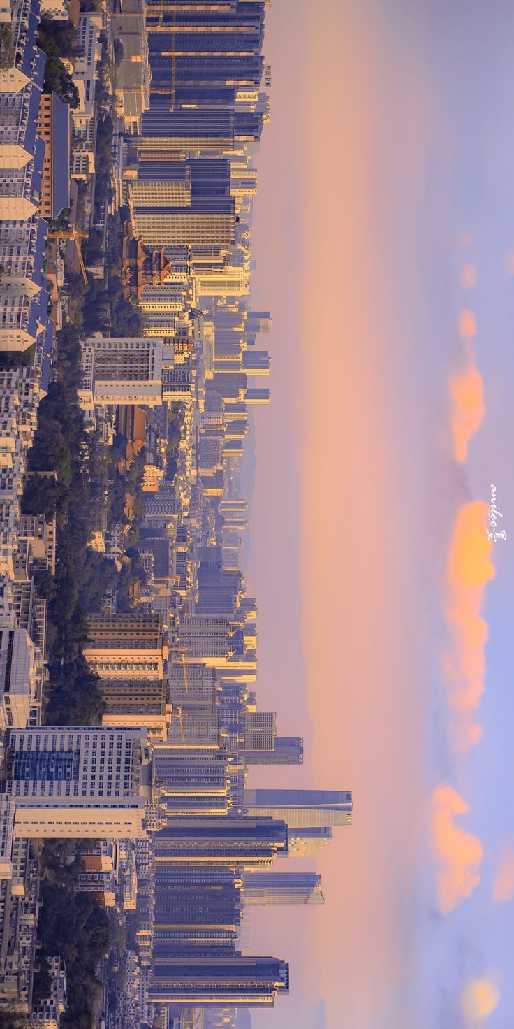 an airplane is flying over a city with tall buildings and clouds in the sky above