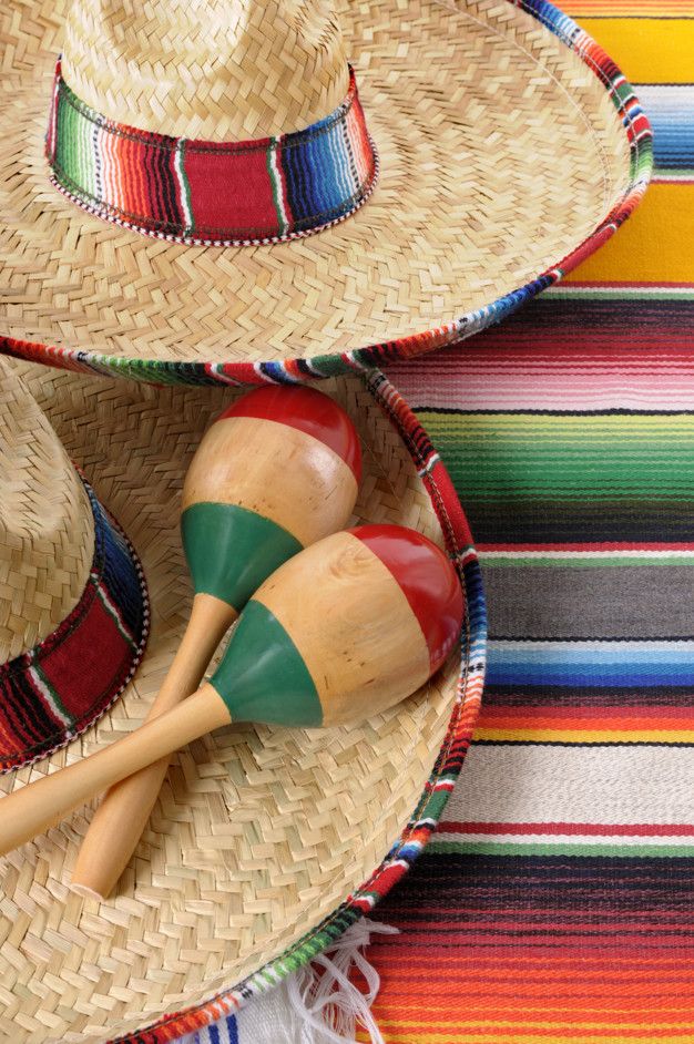 two wooden maracasas and hats on a colorful striped table cloth