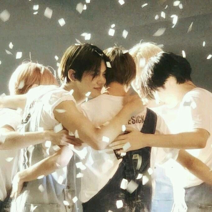 group of young men hugging each other with confetti falling around them