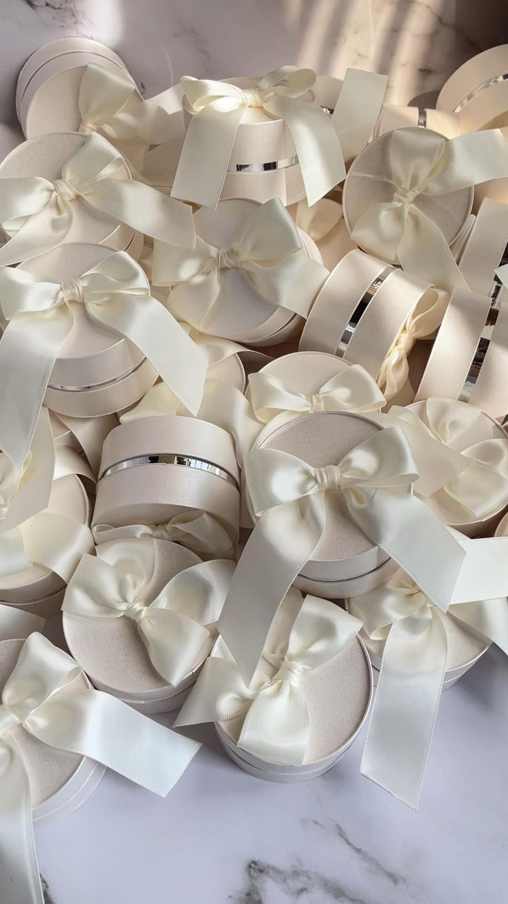 many white boxes with bows on them sitting on a table