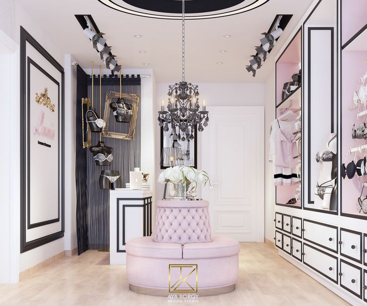 a pink couch sitting under a chandelier next to a white cabinet with drawers