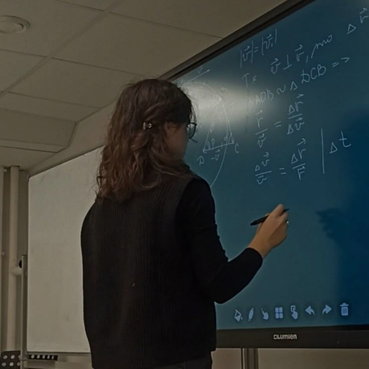 a woman standing in front of a blackboard writing on it