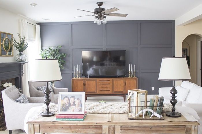 a living room with two lamps, a television and pictures on the coffee table in front of it