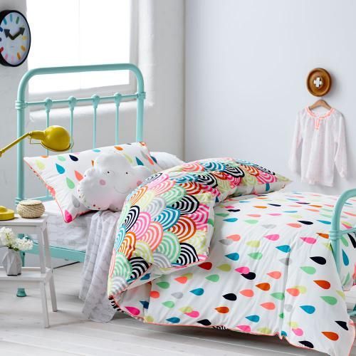 a child's bed with colorful polka dot sheets and pillowcases on it