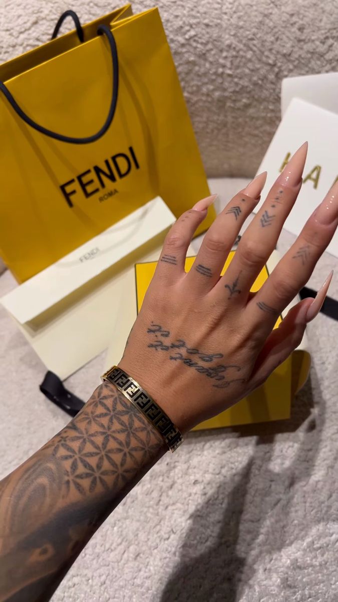 a person's hand with tattoos on it next to a yellow shopping bag and other items